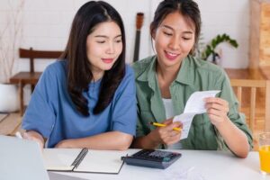 Asian lesbain couple together calculate home budget with paper b