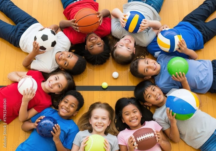 Diverse group of children smiling and holding sports balls on a gym floor Stock Photo Adobe Stock